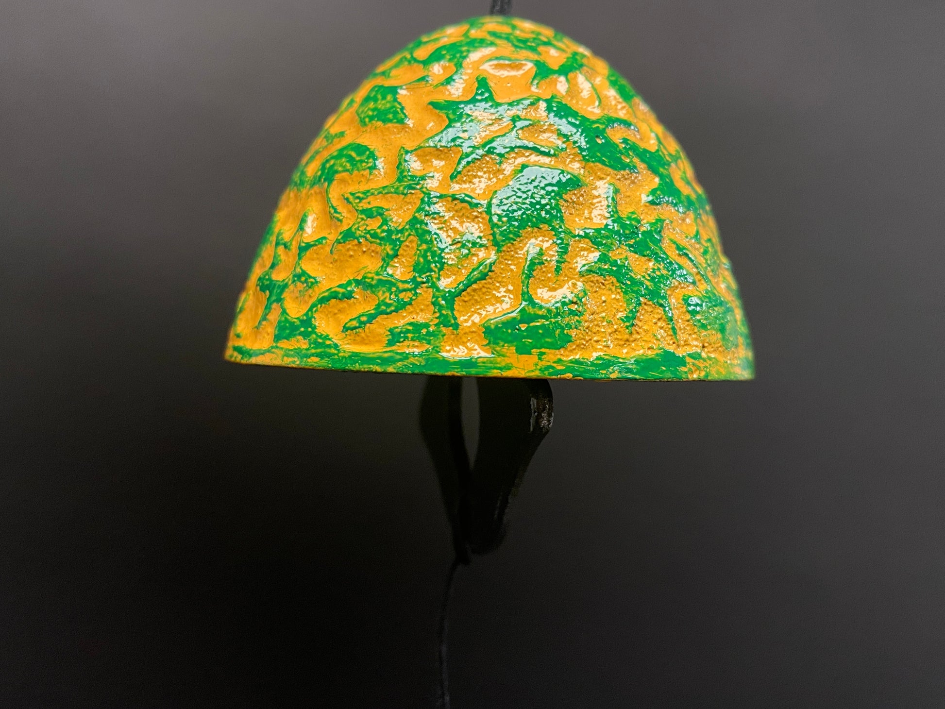 Top-down view of cast iron wind bell with three paper tails spread out showing full patterns