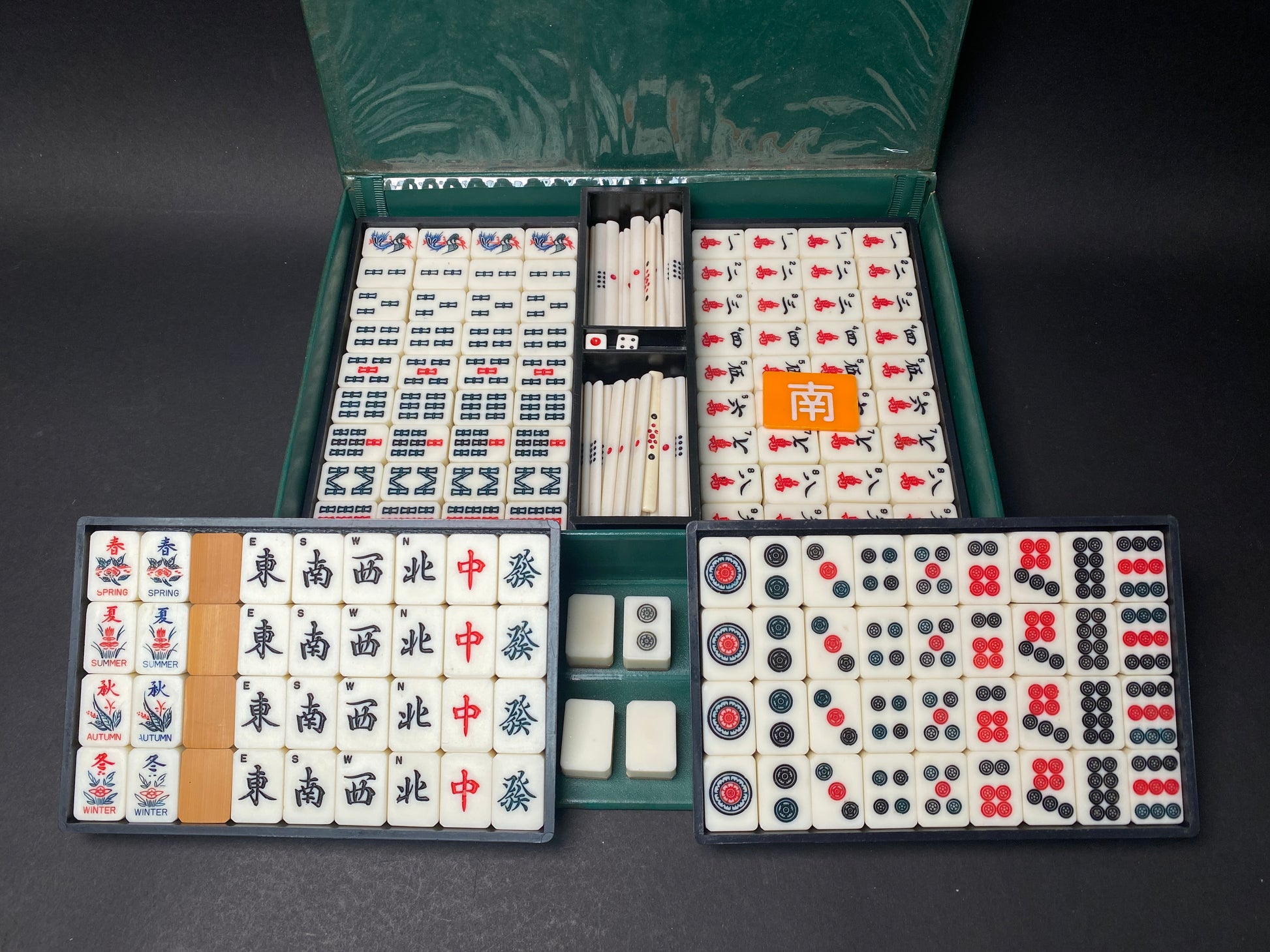 Close-up of bamboo-backed mahjong tiles with cream faces and colored markings