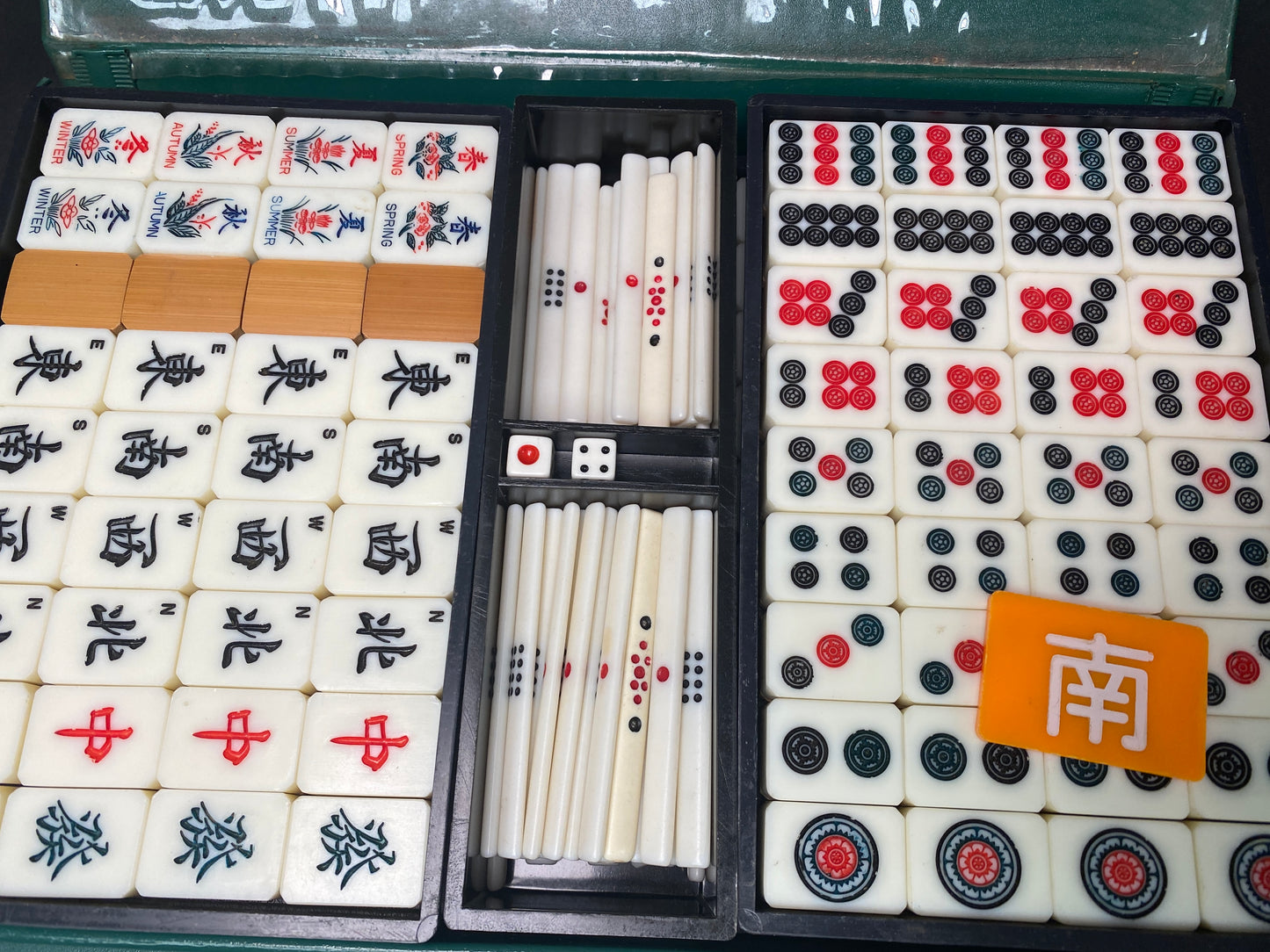 Complete mahjong set with scoring sticks, dice, and orange marker tile