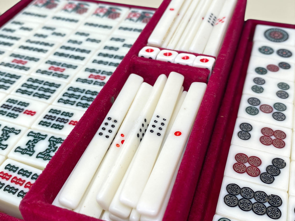 Mahjong tiles with green and red bamboo suit markings in red velvet tray