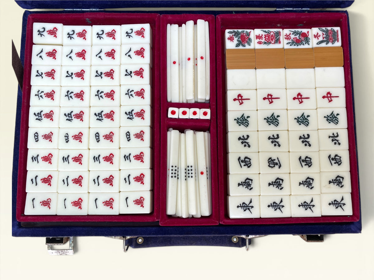 Mahjong flower and season tiles alongside plain bamboo-backed tiles in red velvet tray