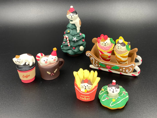 Collection of small figurines including a cat on a tree, ice cream cones, and other items on a black background